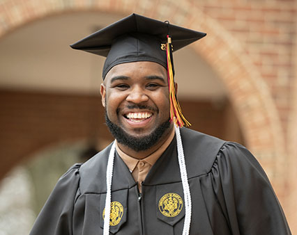 A male student celebrating with graduation cap and gown.